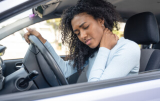 woman in car holding her neck