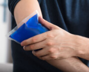 Person Applying Ice Gel Pack On An Injured Elbow