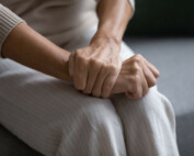 Close up of elderly woman sit on sofa with hands clenched