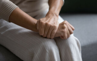 Close up of elderly woman sit on sofa with hands clenched